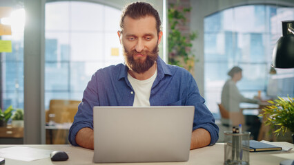 Portrait of a Handsome Man in Creative Agency. Young Stylish Manager with Long Hair and a Beard Looking at Camera. Successful Manager Working in Modern Company.