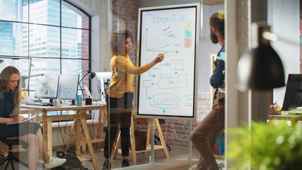 Driven Visionary Businesswoman Leading a Team Meeting in Creative Office Conference Room. Excited Multiethnic Female Showing Presentation on Digital Whiteboard Monitor.