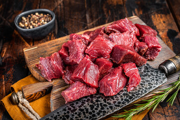 Sliced Raw venison dear meat for a stew, game meat on butcher cutting board. Wooden background. Top view - obrazy, fototapety, plakaty