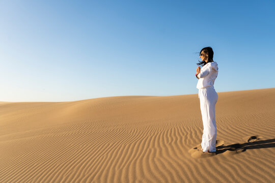 Woman gesticulating namaste in desert