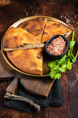 Traditional Ossetian pie sliced on a plate. Dark background. Top view