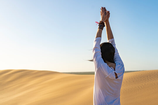 Anonymous woman gesticulating namaste in desert