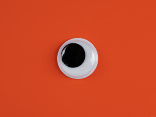 single wobbly googly eye isolated on an orange background with copyspace business logo
