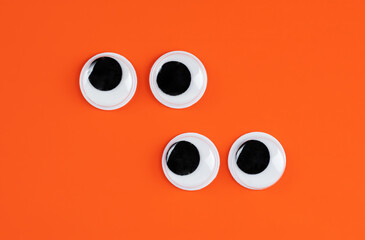 offset pairs of  googly eyes funny Isolated on bright orange background copy space logo