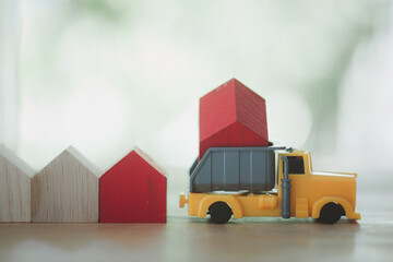 Red truck transports wooden houses. Concept of moving. Construction of new houses, industry,...