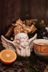 Fototapeta na wymiar Christmas composition angel, cup of coffee, orange on a dark wooden table