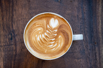 Latte art coffee cup on wooden table, top view