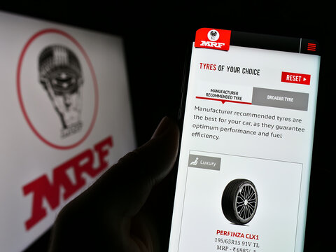 Stuttgart, Germany - 12-11-2022: Person holding cellphone with website of Indian company Madras Rubber Factory (MRF Tyres) on screen with logo. Focus on center of phone display.