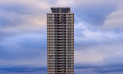 Tall residential apartment building and fluffy clouds in blue hour