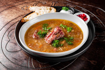 Cabbage soup with meat in white bowl on table