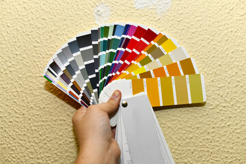 man's hand showing a color palette to apply on a wall. Colour selection. RAL colors