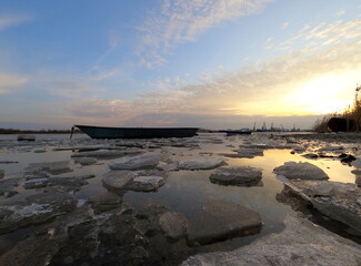 A boat in the ice. Sunset and twilight on the river. Coast line, horizon