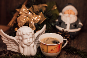 Christmas composition angel, cup of coffee, orange on a dark wooden table