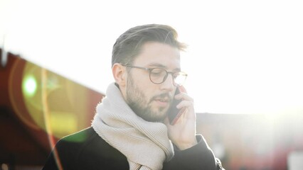 Confident young business man talking on smartphone. Smartphones have become a lifeline for businesspeople on the big city. European businessman talking on the phone walking down the street to work. - Powered by Adobe