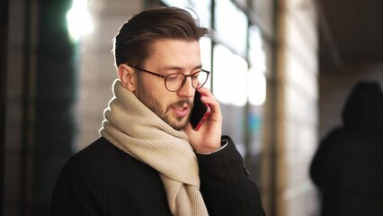 Confident young business man talking on smartphone. Smartphones have become a lifeline for businesspeople on the big city. European businessman talking on the phone walking down the street to work. - Powered by Adobe