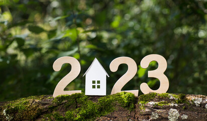 wooden numbers 2023 and Paper House on a green background. happy new year 2023 background banner template. celebrate earth's day. happy New Year!