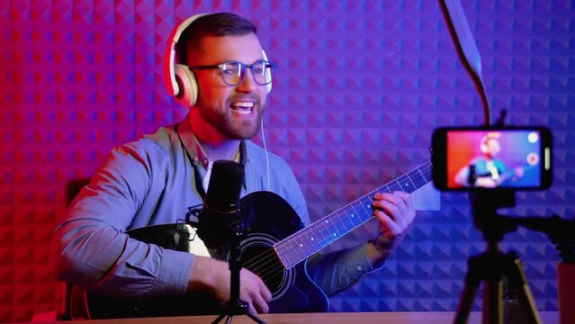 Male vlog influencer performancing music and singing show to streaming digital internet online audience listening at home. Man plays guitar and sing a song. Home entertainer and blogger concept