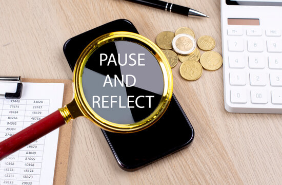 PAUSE AND REFLECT text on the magnifier with smartphone, calculator and coins