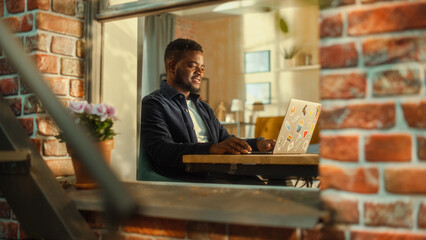 Portrait of a Young Black Male Sitting at a Desk, Thinking, Working on Laptop Computer. Creative...