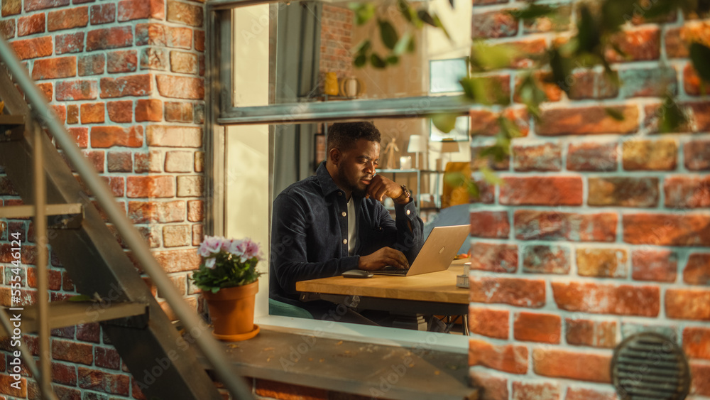 Leinwandbilder young black man using laptop at home. doing inspirational remote work during the day. specialist wor