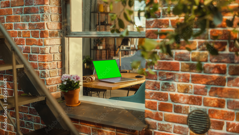 Poster Laptop Computer with Green Screen Mock Up Display Standing on a Table in Stylish Living Room. View from Outside the Window of a Brooklyn-Style Brownstone Multi-Storey Building. Work from Home Concept.
