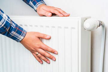 Hands on the radiator of the heating system, selective focus. Background