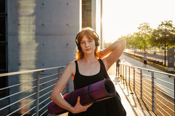 Fototapeta premium Ginger woman in headphones listening music after workout