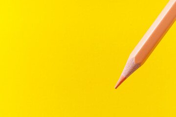 Colored pencil close-up with selective focus on the stylus and a blurred yellow background. Copy...