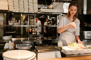 Young woman chef cook preparing meals for a restaurant in kitchen