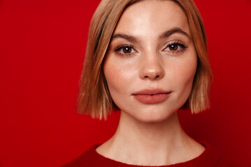 Young blonde woman posing isolated over red studio background