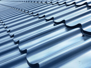 Sheets of glossy blue wave metal roof tiles on the roof of a house close-up
