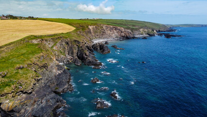 Fototapeta na wymiar Farm fields on the shore of the Celtic Sea, south of Ireland, County Cork. Beautiful coastal area. Turquoise waters of the Atlantic. Picturesque stone hills. Aerial photo. Drone point of view.