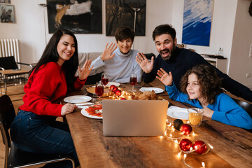 Big happy family using laptop while having christmas dinner at home