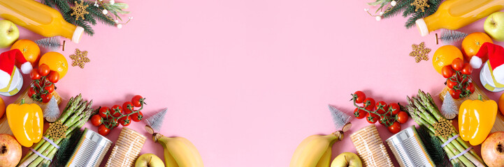 Canned food, pasta, fruits and vegetables for donation decorated for Christmas on pink, charity concept