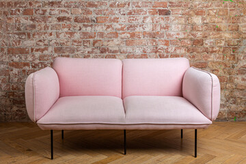 used pink sofa on legs against a grunge brick wall