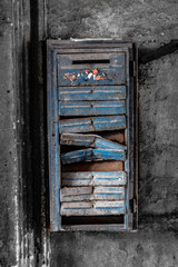 Fototapeta na wymiar Colored blue old rusty broken mailbox hanging on a black and white wall 