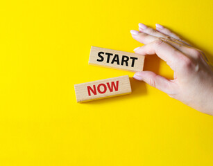 Start now symbol. Wooden blocks with words Start now. Beautiful yellow background. Businessman hand. Business and Start now concept. Copy space.