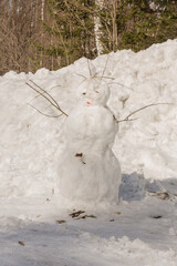 Funny snowman with scarf and hat in winter forest