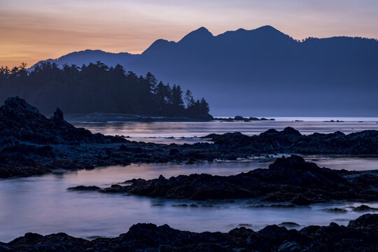Dusk falls over Vancouver Island viewed from an islet in Nuchatlitz Provincial Park; British Columbia, Canada