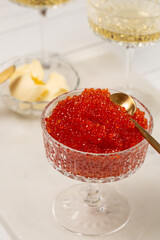 Red caviar in a glass vase on the table with glasses of champagne