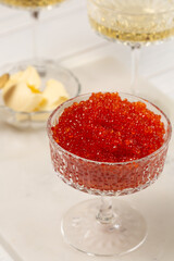 Red caviar in a glass vase on the table with glasses of champagne