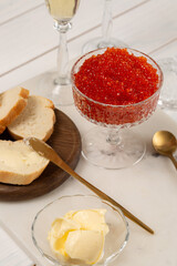 Red caviar in a glass vase on the table with glasses of champagne
