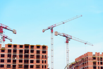 Construction cranes on the construction site of a brick building