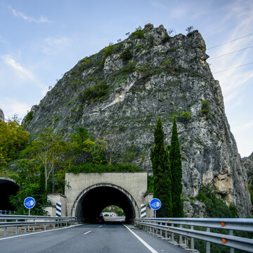 A road going through a dark tunnel with signs indicating the recommended use of headlights; Campillo de Arenas, Jaen Province, Spain