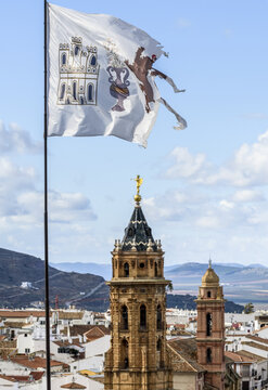 The town of Antequera with church towers and a ripped, weathered flag in the foreground; Antequera, Malaga, Spain