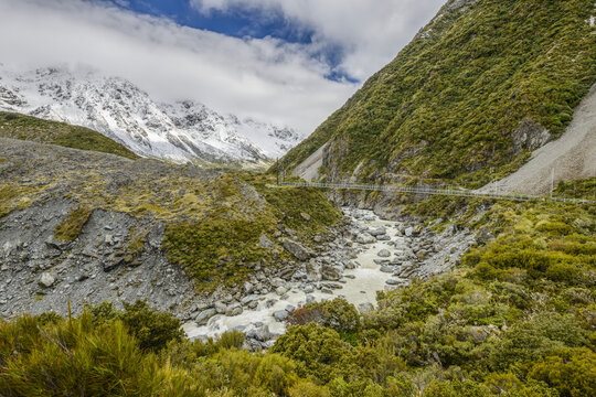 Snowy mountains and hanging bridge along the Hooker Valley Track, Mount Cook National Park; South Island, New Zealand