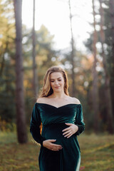 Pregnant happy young woman walking outdoors in forest