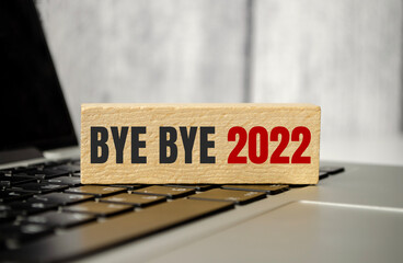 BYE BYE 2022 words on wooden block lying laptop calculator. tax concept