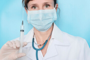 Doctor woman with a stethoscope, European, in a mask and white clothes stands with a bouquet of white daisies. The concept of congratulations, flowers for the day of the physician, nurse.