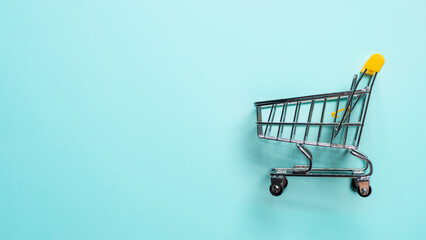 Shopping cart on blue background. Top view or flat lay. Shop trolley at supermarket as sale,...